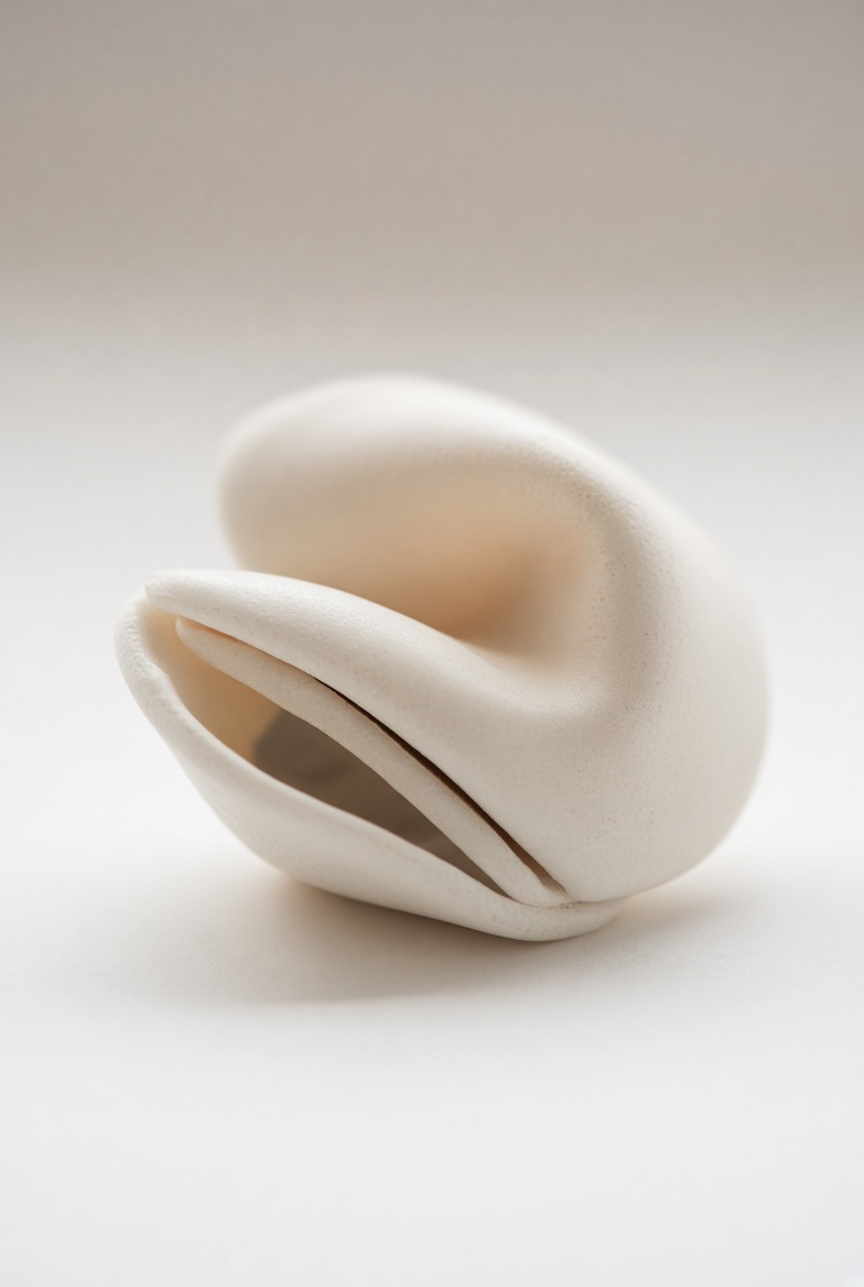 Close-up of a single handmade unglazed porcelain fortune cookie, slightly irregular, bone-white.